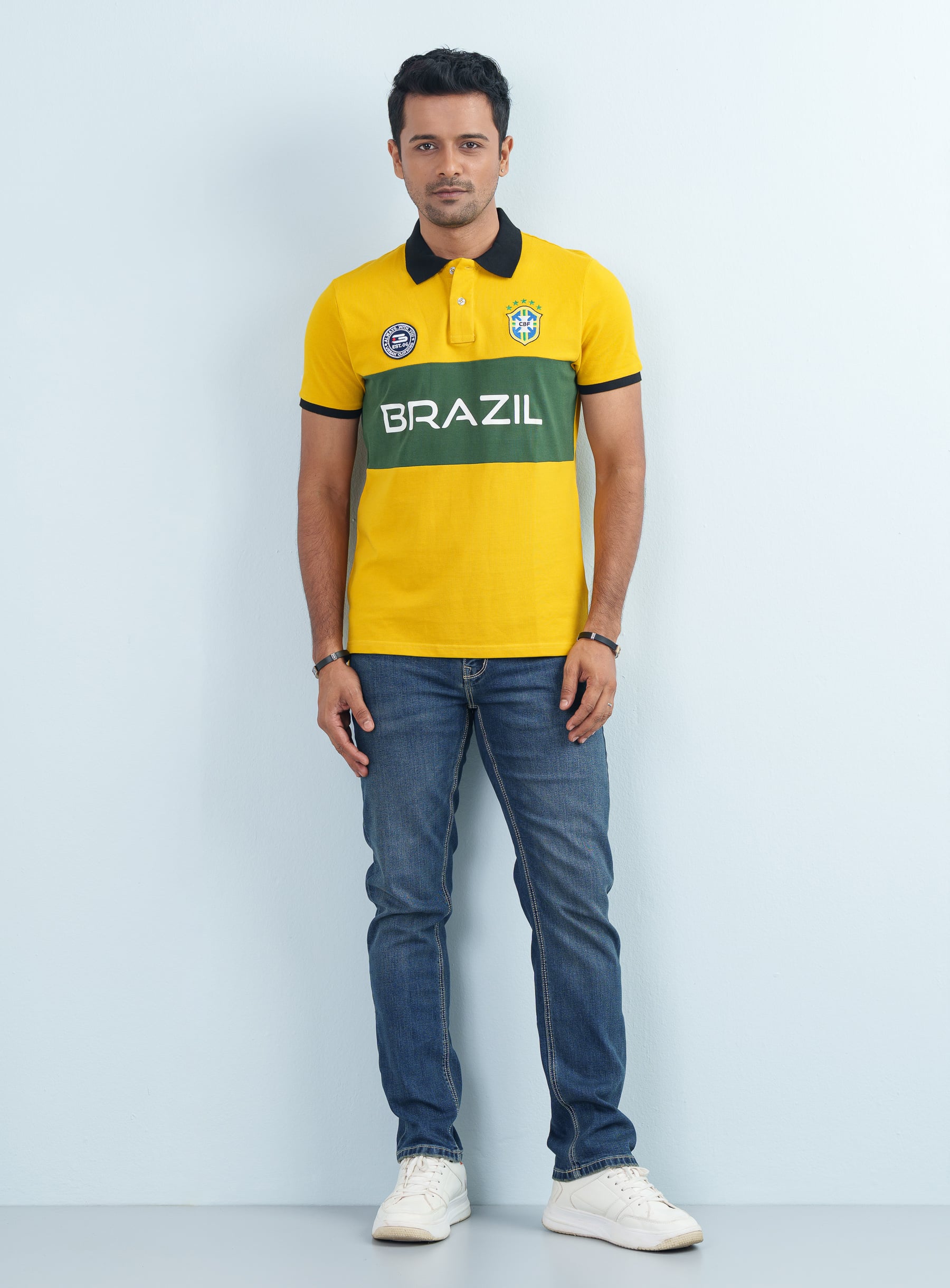 ront look of a man posing in a yellow and green men's Brazil Theme Striped Polo Shirt with blue jeans.