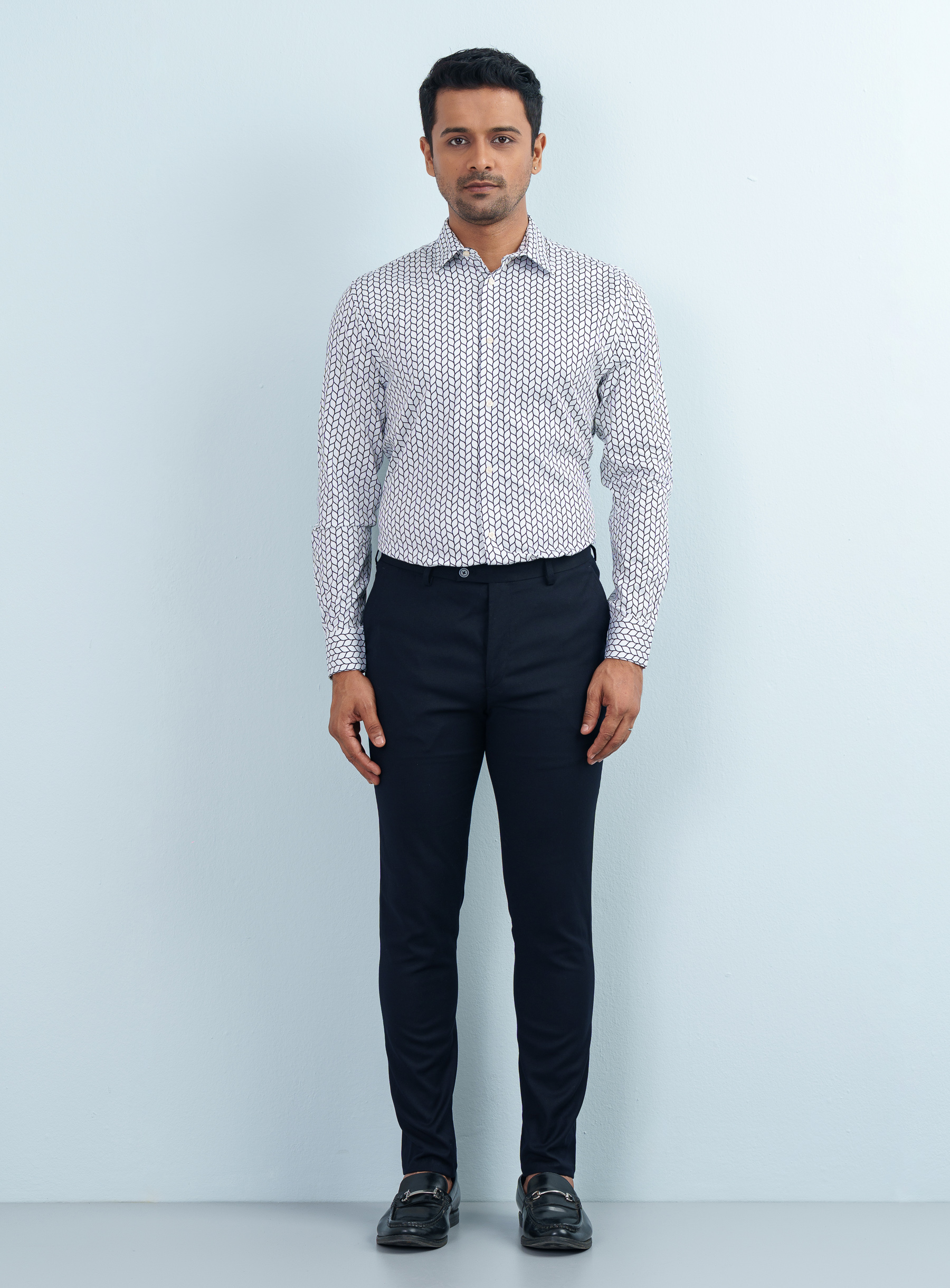 Front view portrait of a male model with hands clasped wearing a monochrome geometric wave print formal shirt